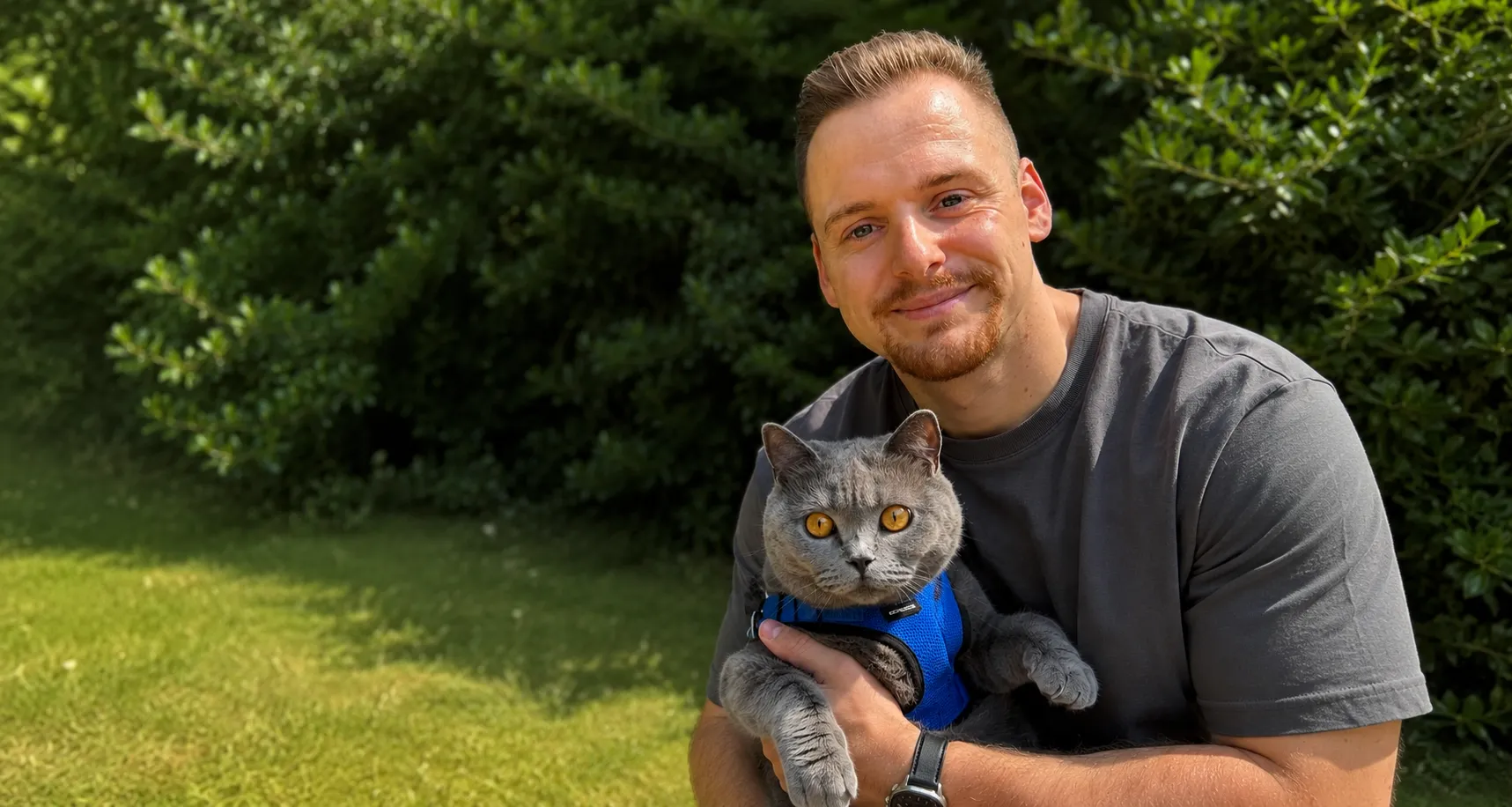 Ich sitze mit meiner grauen Katze im Garten.